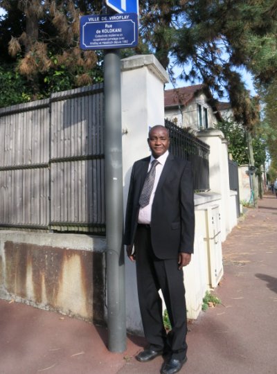 L’autorit de Koloani posant devant la plaque de rue