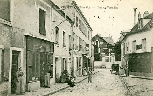 Le coeur du Village, rue de Versailles, avec l’Htel de Morny au fond. Plusieurs commerces, caf billard de l’elyse, la boulangerie CPA (coll. part.)