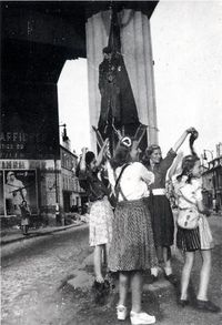 Enthousiasme de la population lors de la Libration de Viroflay. Les habitants saluent le passage de la 2me D.B. On reconnait un mannequin de Hitler pendu  un pilier des Arcades. On voit aussi une affiche de propagande qui subsiste encore. (collection Mairie de Viroflay)