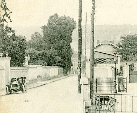 Une voiture  l’allure sportive est gare le long du cimetire. Il semble qu’il n’y avait pas alors l’entre du monument aux morts qui sera lev aprs la guerre 1914-18. La petite entre de la gare avec le chariot  bagages est rest utilis trs tard. (coll. part.)