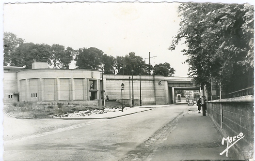 Le pont et la gare ont t refaits en bton en 1938. Seuls les quais sont sur le terre-plein. Vue large du btiment voyageurs avec au premier plan la rue Anatole France et l’esquisse du jardinet permettant un demi-tour des bus. CPSM N/B bords dentels Marco.  (coll. part.)