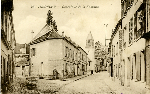 La fontaine du Village. Sur la place, quelques chaises du petit caf et en face quelques boutiques. CPA circule (coll. part.)